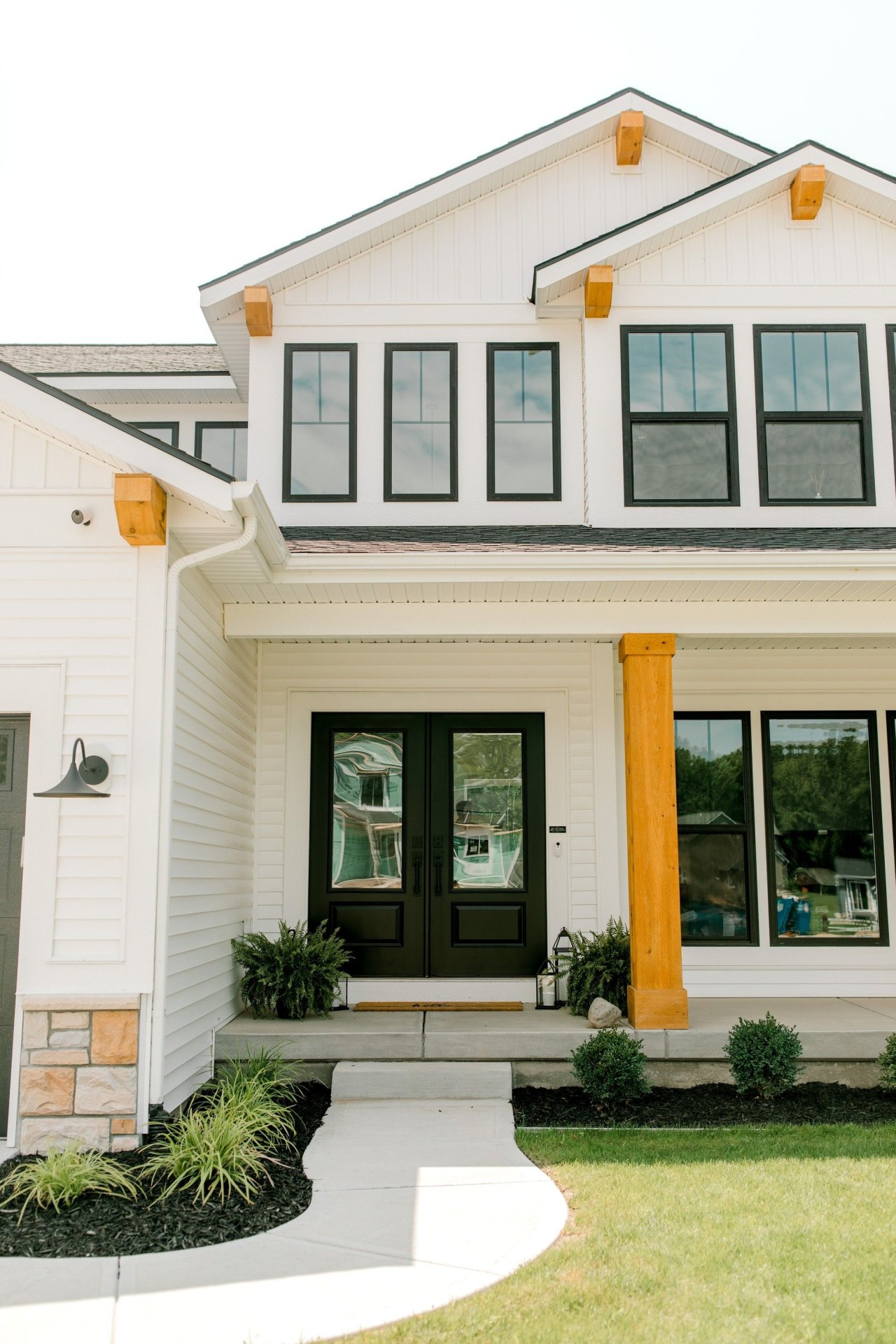 Modern Farmhouse Entry With Black Trim Windows and Wood Accents