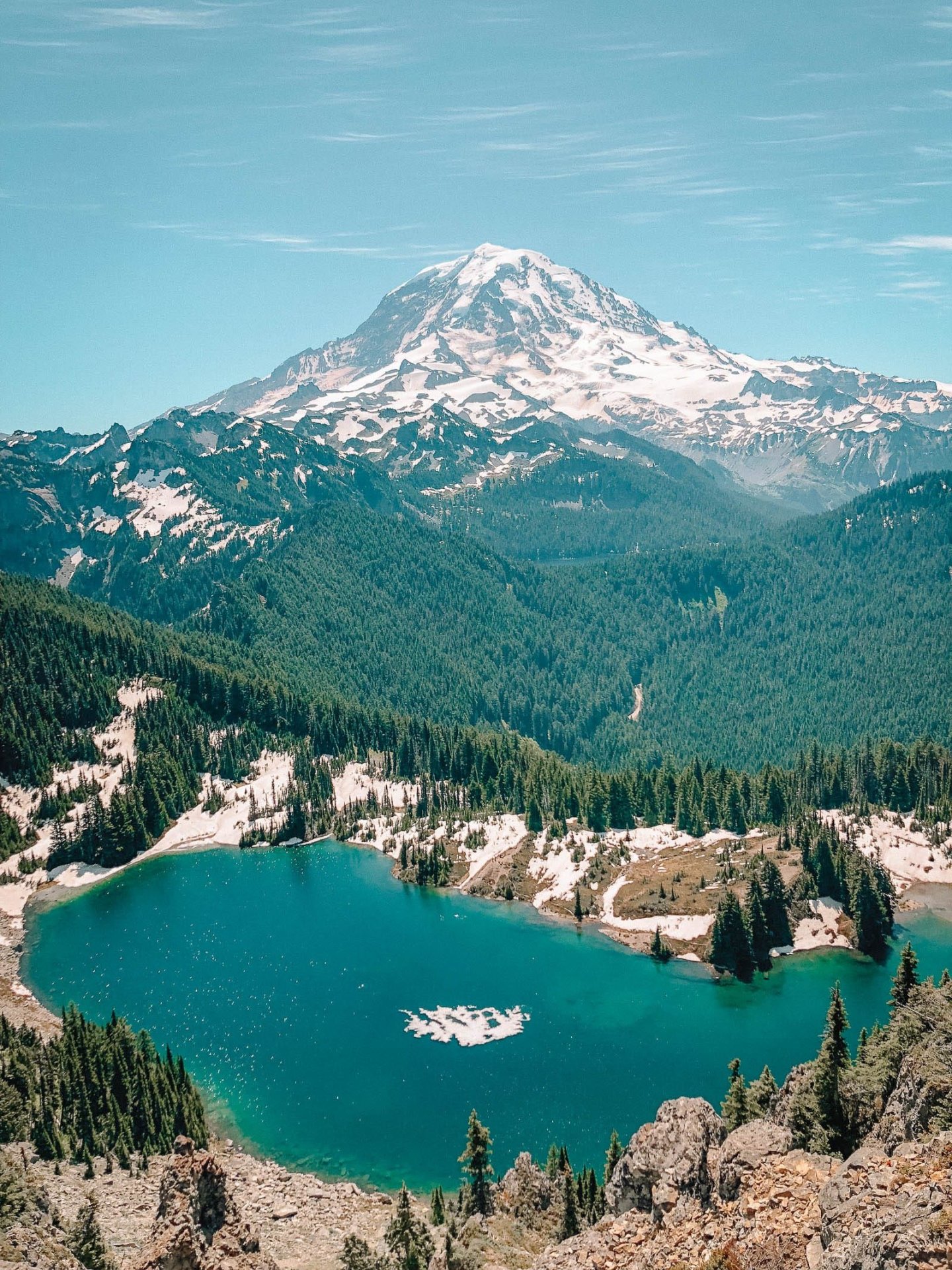 Snow-capped mountain with turquoise alpine lake and lush forest