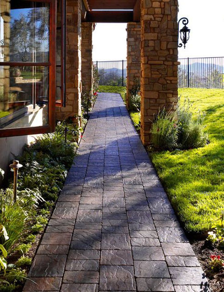 Stone Column Walkway with Stamped Concrete Path and Lush Landscaping